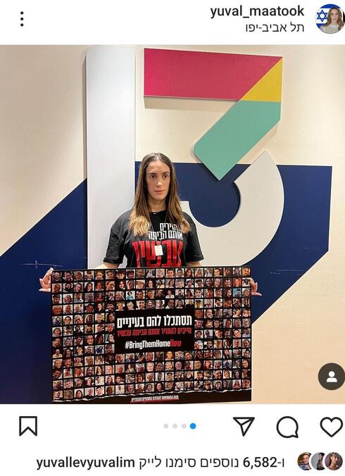 יובל מעתוק מניפה את השלט עם תמונות החטופים